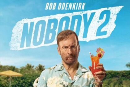 Official movie poster for Nobody 2, featuring Bob Odenkirk as Hutch Mansell, bruised and with cuts on his face, sitting on a poolside chair in a Hawaiian shirt and shorts, holding a grenade in one hand and a tropical drink in the other. The tagline reads "NOBODY RUINS HIS VACATION."