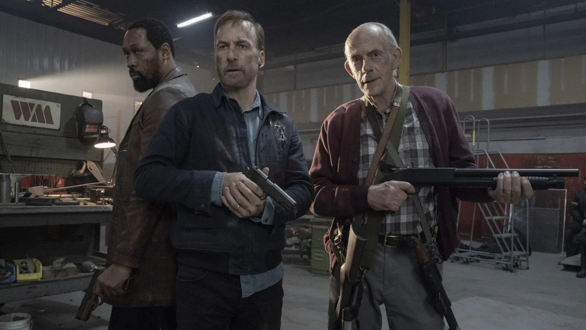 Bob Odenkirk, RZA, and Christopher Lloyd holding firearms, looking determined in a gritty setting from the movie Nobody.