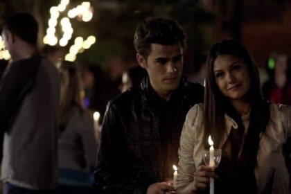 Stefan Salvatore and Elena Gilbert holding candles at the outdoor comet viewing event in Mystic Falls.